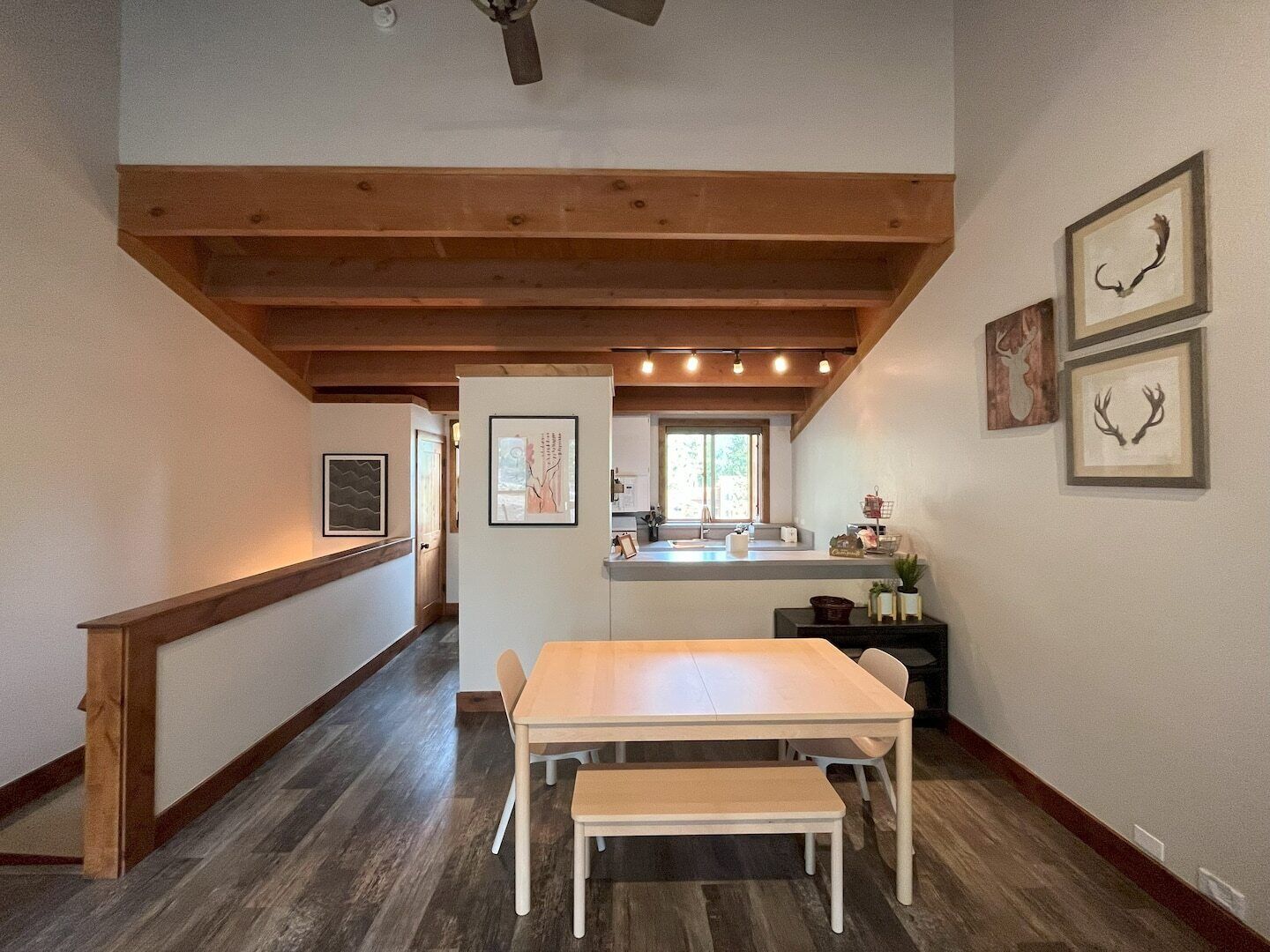 A spacious kitchen with wooden beams, a dining area with a bench, and framed artwork on the walls.