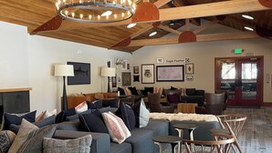Eine großzügige Lobby mit einer breiten Eckcouch, einem runden Kronleuchter und einem Kamin.