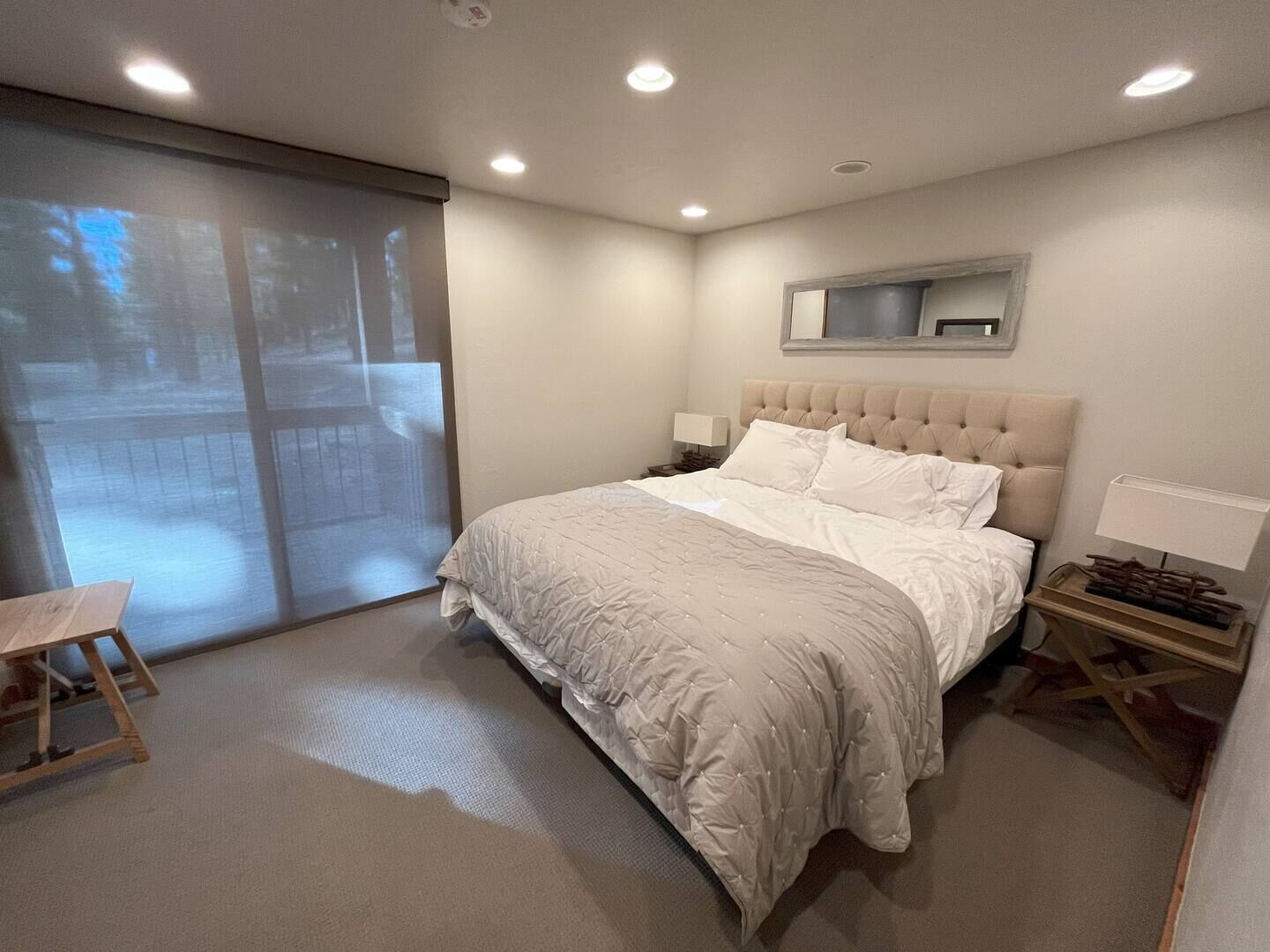 Een slaapkamer met een groot bed, een schuifpui naar een balkon en een klein houten tafeltje.