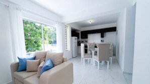 Una sala de estar moderna con un sofá beige y una zona de comedor con una mesa y sillas.