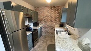 Una cocina compacta con un refrigerador de acero inoxidable, un microondas y un lavamanos.