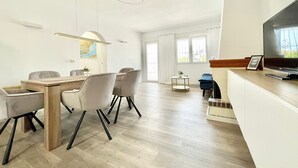 Ein modernes Wohnzimmer mit Essbereich, Fernseher und Kamin.
