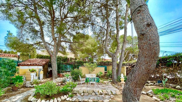 Ein Garten mit einer Terrassenanlage, einem gepflasterten Weg und einem kleinen Gebäude mit einem Ziegeldach.