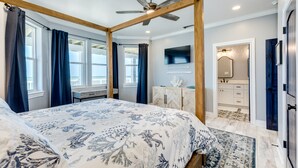 A bedroom with a large bed, a ceiling fan, and a view of the ocean through the windows. - Beachfront Luxury Retreat – Oceanfront, Family & Pet-Friendly Paradise (Freeport)