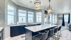 A modern kitchen with a large island, dark cabinets, and large windows. - Beachfront Luxury Retreat – Oceanfront, Family & Pet-Friendly Paradise (Freeport)