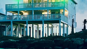 A multi-story beachfront property with balconies, a covered lower level, and a view of the ocean. - Beachfront Luxury Retreat – Oceanfront, Family & Pet-Friendly Paradise (Freeport)