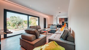 A modern living room with a sofa, ottoman, and coffee table. A television is visible in the background.