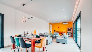 A modern living space with a dining area, a sofa, and a large window.
