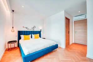 Een moderne slaapkamer met een bed, een wandlamp en een houten deur.