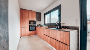 A modern kitchen with wooden cabinets, a large window, and a built-in oven.