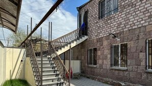 Un escalier menant à un bâtiment en briques doté de nombreuses fenêtres, d’une terrasse carrelée et de plantes en pot.