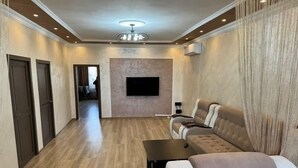 Un salon moderne avec un canapé, une table basse et un téléviseur à écran plat fixé au mur.
