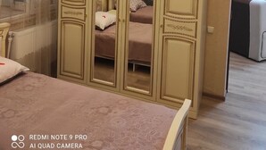 Une chambre à coucher avec un lit, une armoire avec un miroir et une fenêtre avec des rideaux.