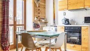 A modern kitchen with wooden cabinets, a glass dining table, and a built-in oven. - The Loving Cabin  (Pragelato-Ruà)