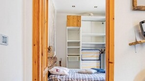 A narrow hallway leading to a bedroom with a bed, wooden furniture, and a built-in wardrobe. - The Loving Cabin  (Pragelato-Ruà)