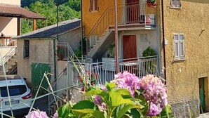 Ein zweistöckiges Haus mit Balkon, Treppe und Blick ins grüne Umland.