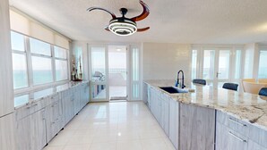 Una cocina moderna con una isla grande, un ventilador de techo y vistas al exterior.