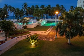 Un complexe hôtelier doté d’une piscine, de palmiers et offrant une vue sur l’océan.