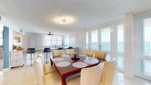 Un vaste espace dédié à la salle à manger, avec une grande table, de nombreuses chaises et une cuisine en arrière-plan.