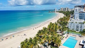 Un resort en la playa con piscina, palmeras y vista al océano.
