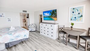 A bedroom with a bed, a dresser, a TV, and a painting. - Stunning Ocean Front Efficiency (Myrtle Beach)