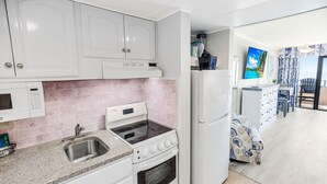 A modern kitchen with white cabinets, a built-in oven, a microwave, and a stainless steel sink. - Stunning Ocean Front Efficiency (Myrtle Beach)