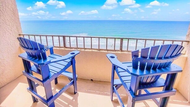 A balcony with two blue Adirondack chairs facing a beach. - Stunning Ocean Front Efficiency (Myrtle Beach)