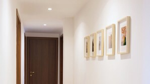 A hallway with a wooden door at the end, a tiled floor, and four framed pictures on the wall. - Le Stanze di Archimede (Syracuse)