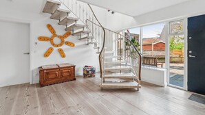 Um quarto espaçoso com piso de madeira, escada moderna e uma grande janela com vista para o exterior.
