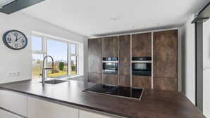 Uma cozinha moderna com uma janela grande, eletrodomésticos de aço inoxidável e forno embutido.