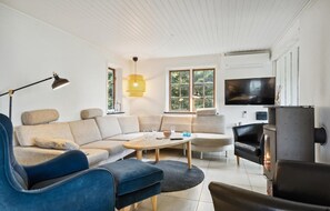 Relax in this stylish living room with a large sofa, armchair, and fireplace.