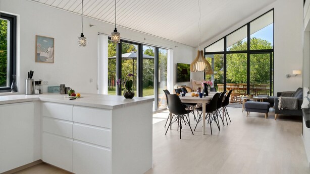 Une cuisine moderne dotée d’un grand îlot central, de chaises noires et d’un coin repas avec une table et des chaises.