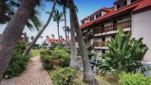 Um hotel de vários andares com telhado vermelho, rodeado por palmeiras e vegetação.
