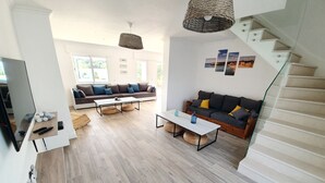 Àmplia zona d'estar amb un disseny modern, que inclou un sofà, una taula de centre i una escala.