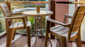 A balcony with a round table and four chairs, overlooking a cityscape during sunset. - Kallia Apartment (Chania)