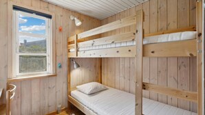 Habitación con literas, paredes de madera, una ventana con vistas y un escritorio con silla.