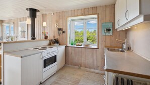Una cocina moderna con paneles de madera, un ventanal y vistas al verdor exterior.
