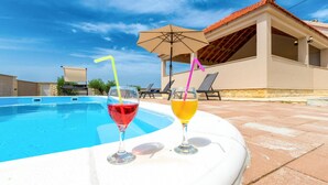 A swimming pool with lounge chairs and a building with a tiled roof. - Amazing home in Benkovac (Benkovac)