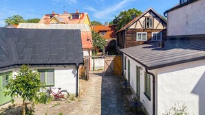 A narrow cobblestone alley with buildings on either side, a bicycle, and a small table with chairs.