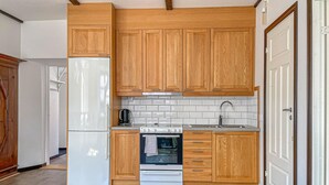 A kitchen with wooden cabinets, a built-in oven, a sink, and a refrigerator.