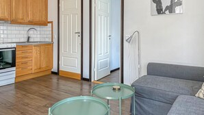 A compact living space with a kitchenette, a grey sofa, and two small round tables.
