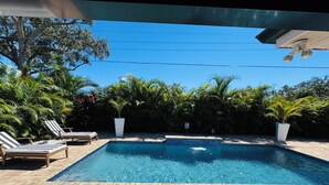 Piscina com espreguiçadeiras e plantas em vasos.