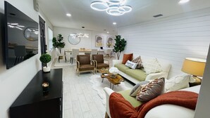 Uma sala de estar moderna com sofá, poltronas, mesa de centro e televisão na parede.