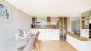 A modern kitchen with white cabinets, a glass dining table, and a coffee machine. - Lydia Apartment (Chania)