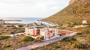 A coastal area with buildings, a road, and a cliff. - Lydia Apartment (Chania)