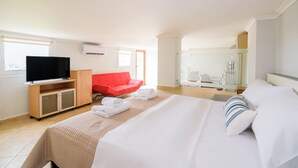A hotel room with a bed, a television, a red chair, and a white wardrobe. - Lydia Apartment (Chania)
