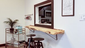 Une cuisine avec un plan de travail en bois, un porte-ustensiles suspendu et une carte encadrée accrochée au mur.