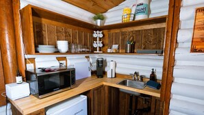 A compact kitchen with wooden cabinets, a microwave, a coffee maker, and a sink. - Hiker's Haven Summary (Mount Laguna)