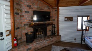 A cozy room with a brick fireplace, a mounted television, and a bunk bed. - Hiker's Haven Summary (Mount Laguna)
