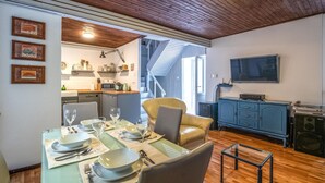 A dining area with a table set for four, a kitchen in the background, a blue cabinet with a TV, and a staircase leading to an upper floor. - 2 bedroom gorgeous home in Labin (Labin)